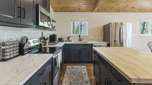 Une cuisine moderne avec des meubles de couleur sombre, un plafond en bois et un plan de travail en marbre.
