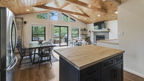 Une cuisine moderne avec des poutres en bois, un îlot central et un coin repas comprenant des chaises et une table.