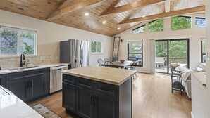 Une cuisine spacieuse avec des meubles de couleur sombre, un îlot central en bois et une grande fenêtre.