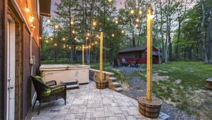 Une terrasse avec des sièges d’extérieur, un jacuzzi et des guirlandes lumineuses.