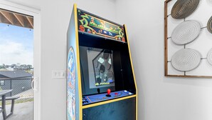 Ein altes Arcade-Spielgerät mit Joystick und bunten Bedienelementen, an einer Wand mit Metallrahmen befestigt.