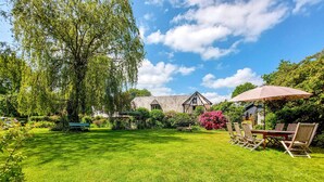 A well-maintained garden with a lawn, a wooden bench, and a dining table with chairs. - Lovely home in Thierville (Thierville)