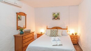 A neatly arranged bedroom with a wooden bed, bedside tables, a dresser, a mirror, and a framed picture on the wall. - Casa Pulirio Antequera - La Higuera by Ruralidays (Málaga)