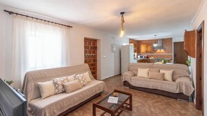 A living room with two sofas, a coffee table, and a kitchen in the background. - Casa Pulirio Antequera - La Higuera by Ruralidays (Málaga)
