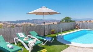 A backyard with a swimming pool, green lawn, and lounge chairs. - Casa Pulirio Antequera - La Higuera by Ruralidays (Málaga)