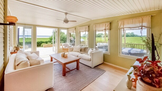 A spacious living room with a large sofa, a coffee table, and a view of a green landscape through large windows. - Awesome home in Harlösa with lake view (Harlösa)