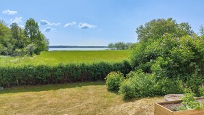 A garden with a view of a lake, wooden raised beds, and a variety of plants. - Awesome home in Harlösa with lake view (Harlösa)