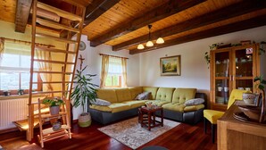 Ein gemütliches Wohnzimmer mit Holzboden, einem grünen Sofa, einem Holzschrank und einer Leiter.