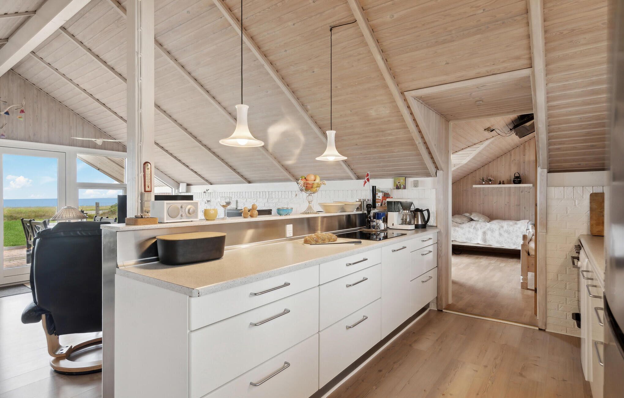 A modern kitchen with white cabinetry, a large island, and pendant lighting.