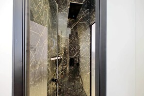 A bathroom with a glass door, marble walls, and a shower area. - Youroom Quattro Fontane - Rooms (Rome)