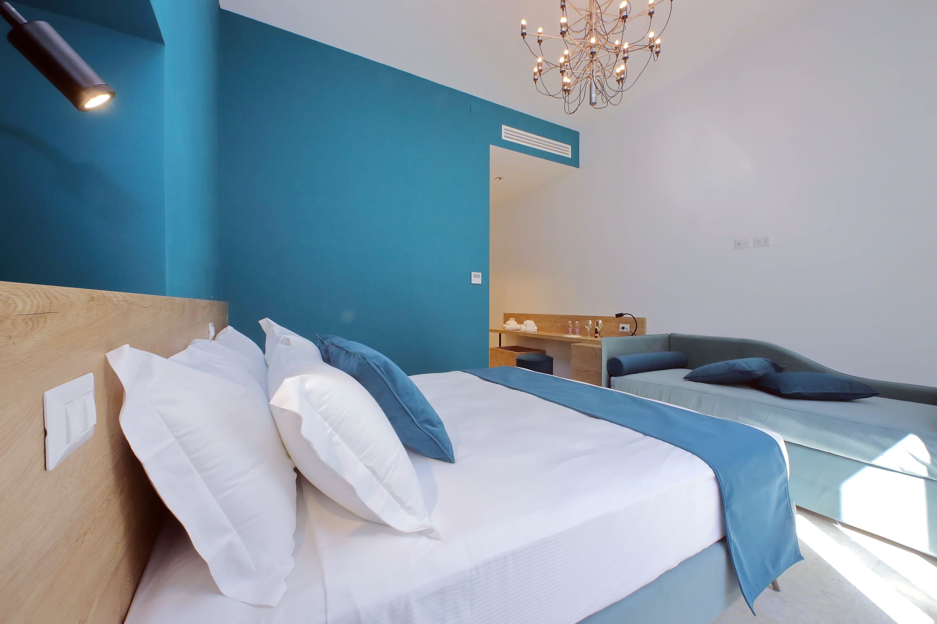 A modern hotel room with a large bed, a desk, and a mirror.