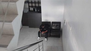 A staircase with metal railings, a person sitting on a bench, and a reception desk in the background. - Hospedaje Moralillos (Yurimaguas)