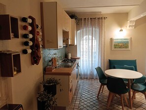 Una cocina compacta con comedor, suelo de baldosas y ventana con cortinas.