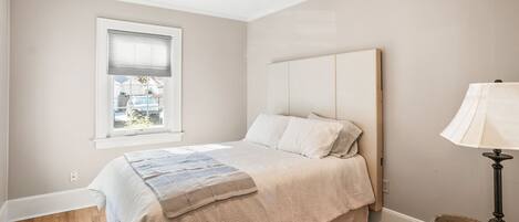 A bedroom with a bed, a window, a ceiling fan, and a lamp.