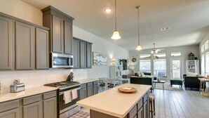 Una cocina moderna con armarios grises, una isla central y una zona de comedor con mesa y sillas de vidrio.