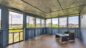 A covered porch with a view of a grassy area and buildings in the distance. - Deck & Fenced-In Yard: Texas Escape! (Freeport)