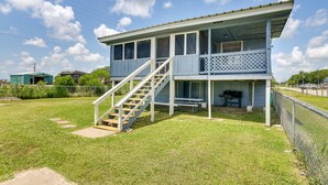 A two-story house with a porch, a staircase, and a barbecue grill. - Deck & Fenced-In Yard: Texas Escape! (Freeport)