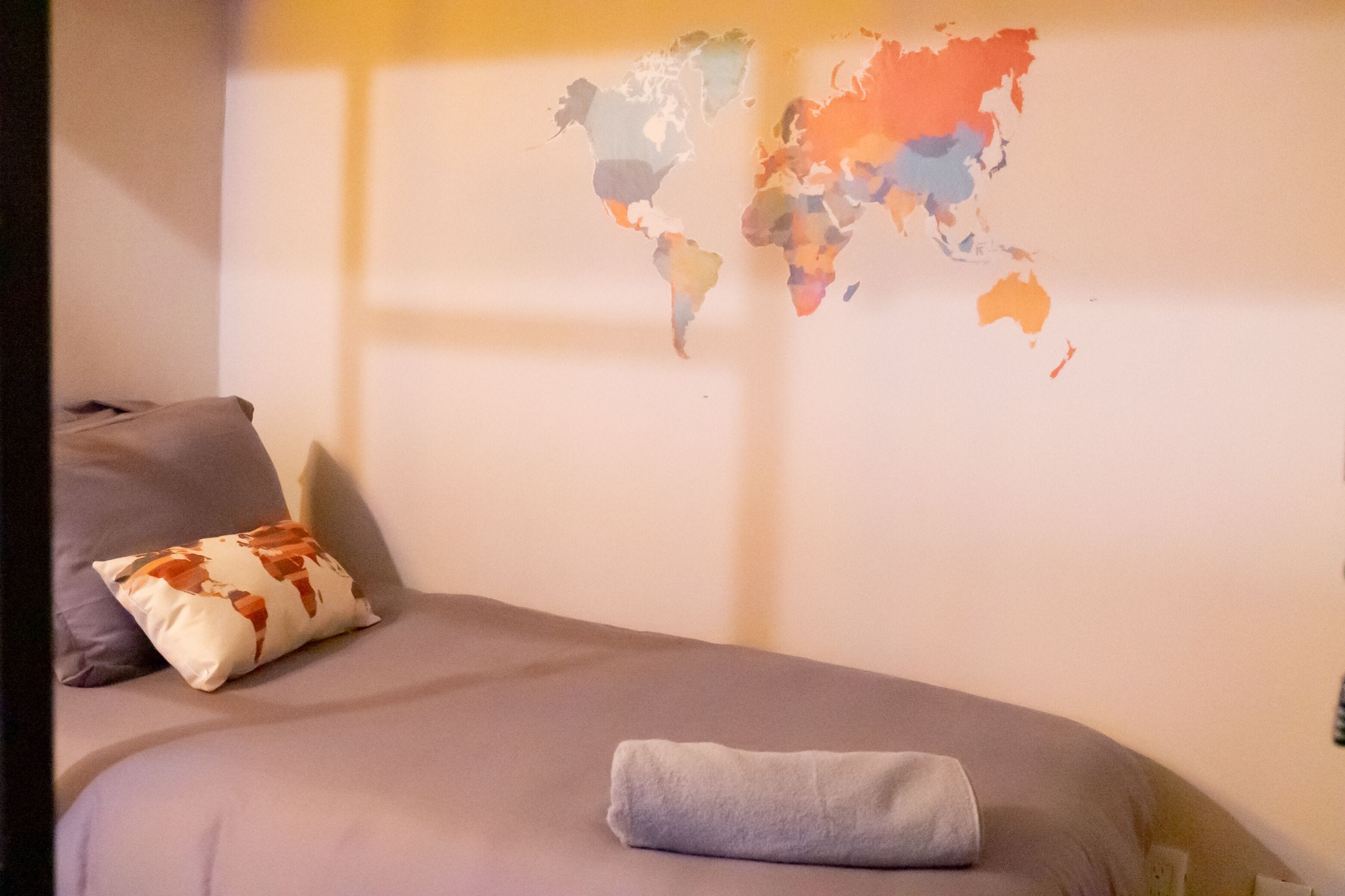 A bed with a grey blanket and a pillow with a cow print design.