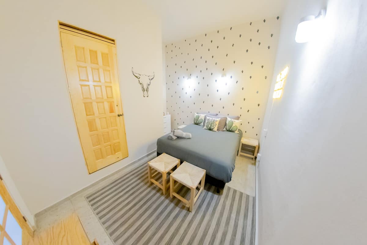 Ein Schlafzimmer mit einem Bett, zwei Nachttischen, einer Tür und einer Wand mit Kaktusaufklebern.