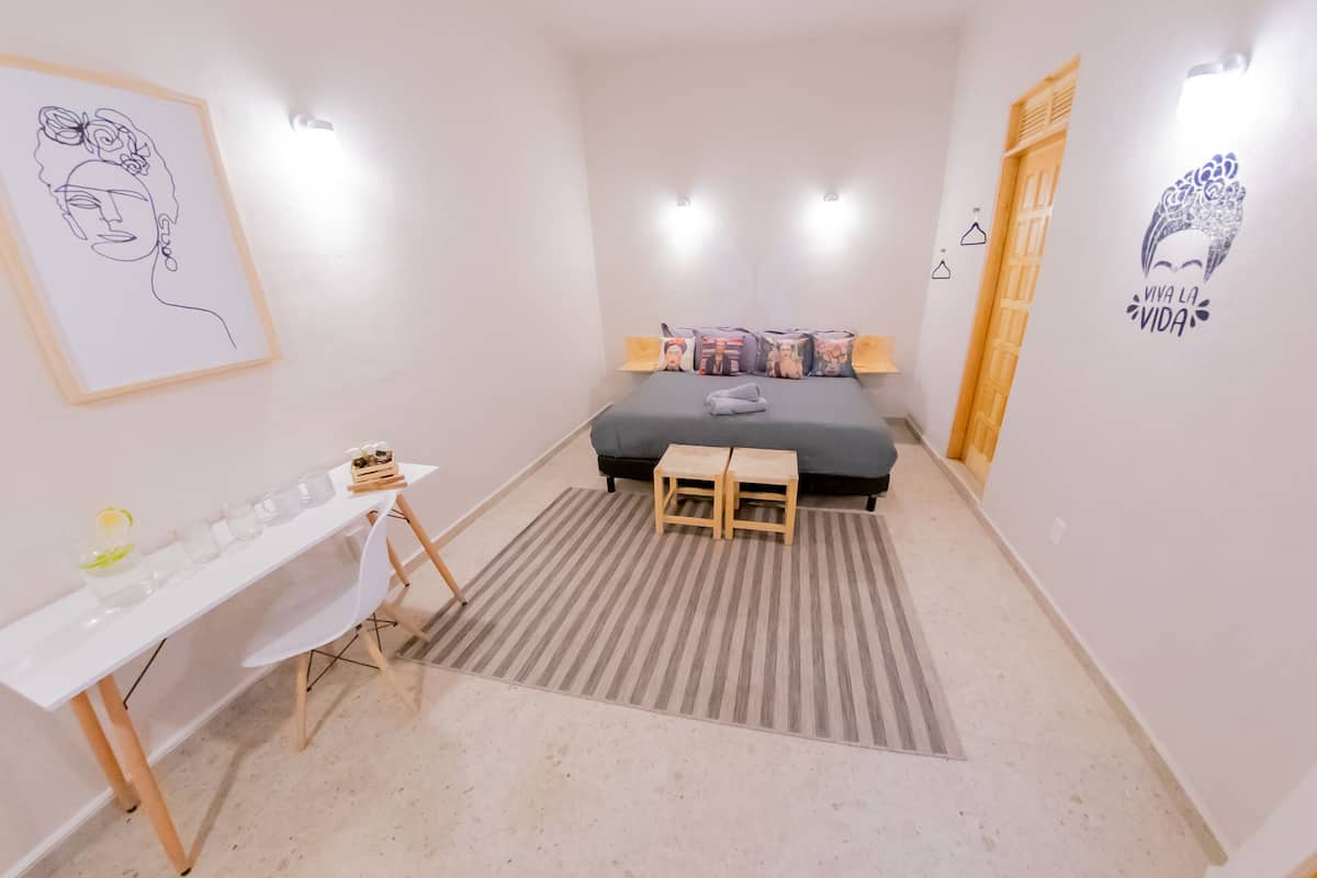 Ein Schlafzimmer mit Bett, Nachttischen, einem Schreibtisch und einem Teppich.