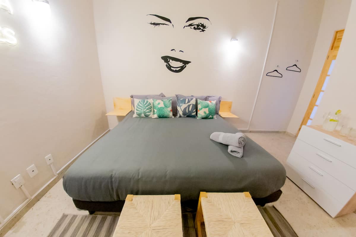 Ein ordentlich eingerichtetes Schlafzimmer mit Bett, Nachttischen, einer Kommode und einer Wanddekoration.