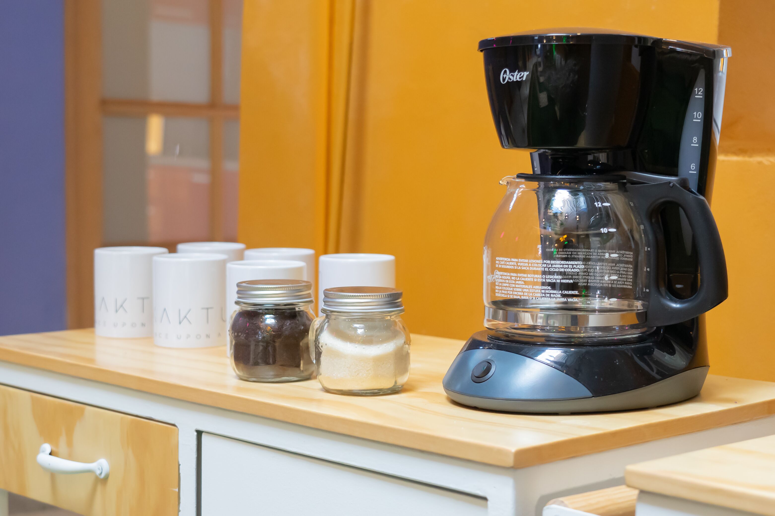 A coffee maker on a kitchen counter with jars of ingredients.