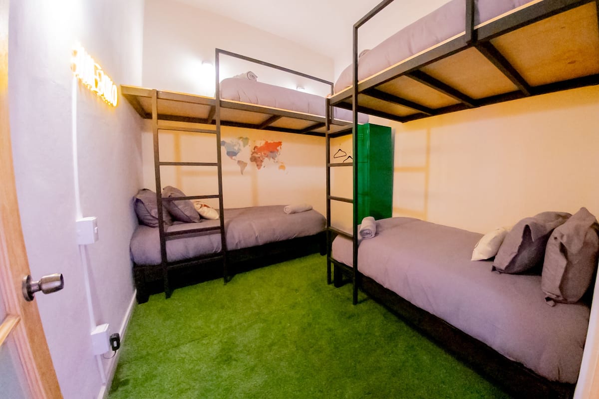 Ein Zimmer mit Etagenbetten, einem grünen Teppich und einer Weltkarte an der Wand.