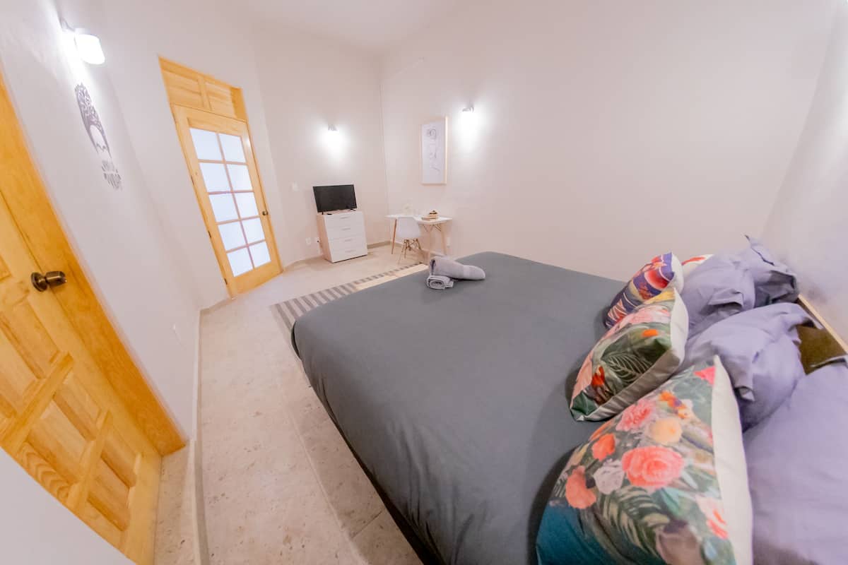 Ein Schlafzimmer mit einem Bett, Kissen, einem Schreibtisch und einem Stuhl.