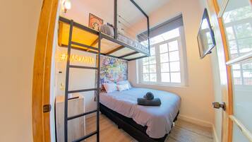 Um quarto com uma cama beliche, uma escrivaninha, uma janela com vista e uma parede com um mural colorido.