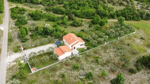 Vista aérea de una casa con techo rojo, rodeada de vegetación y un camino de tierra.