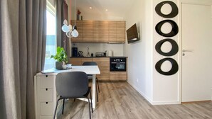 A modern kitchen with wooden cabinets, a built-in oven, and a dining area with a table and chairs. - Cozy home in Tvååker with kitchen (Tvååker)