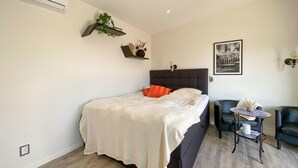 A bedroom with a bed, a small round table with a chair, a wall-mounted shelf with plants, and a framed picture on the wall. - Cozy home in Tvååker with kitchen (Tvååker)