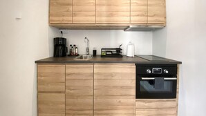 A compact kitchen with wooden cabinetry, a built-in oven, and a coffee maker. - Cozy home in Tvååker with kitchen (Tvååker)