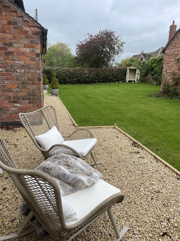 A patio area with wicker chairs and a small garden.