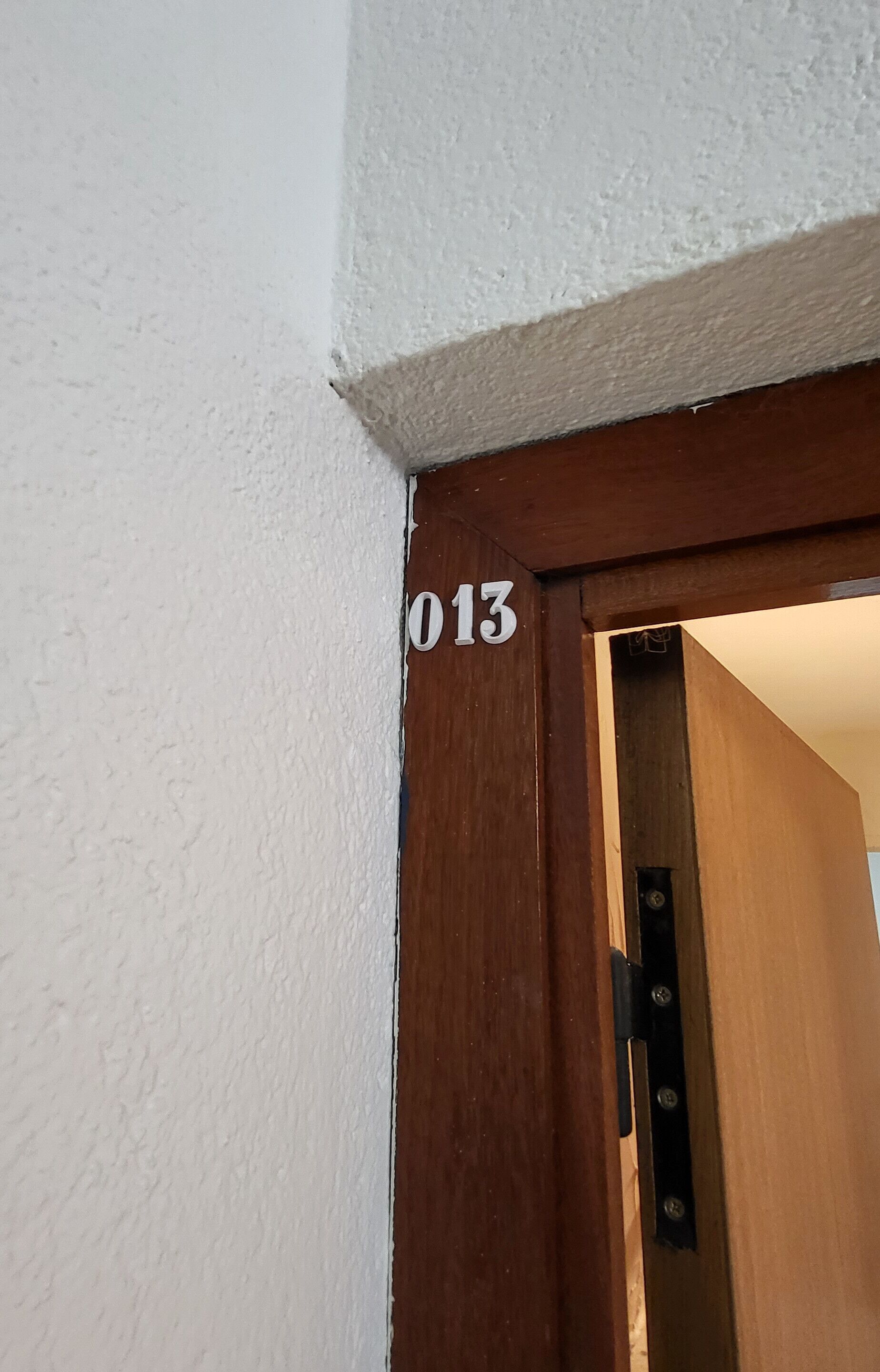 Une porte avec le numéro « 013 » sur un mur blanc.