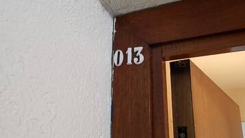 Une porte avec le numéro « 013 » sur un mur blanc.