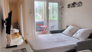 Un dormitorio con cama, escritorio, silla, televisor y ventana.
