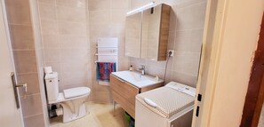 Ein kleines Badezimmer mit Toilette, Waschbecken und Spiegel.