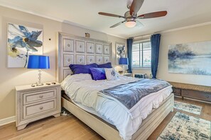 Ein Schlafzimmer mit einem großen Bett, einem Nachttisch, einem Deckenventilator und Bildern an den Wänden.