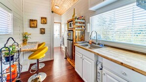 Una cocina con armarios de madera, horno empotrado, lavabo y una ventana con persianas.