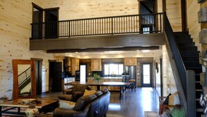 A spacious loft-style interior with a high ceiling, a mezzanine level, a kitchen, and a dining area. - New! Juniper Ridge Luxury Lodge @ East Zion & Bryce (Orderville)