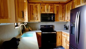 A kitchen with wooden cabinets, a stainless steel refrigerator, a microwave, and a stove.