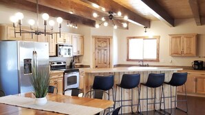 Een moderne keuken met houten kastjes, een roestvrijstalen koelkast, een ingebouwde oven en een bar met vier krukken.