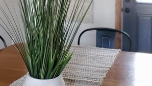 Een eettafel met een potplant, een geweven placemat en een plafondlamp.