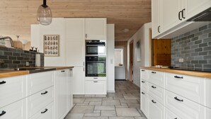 Een moderne keuken met witte kasten, een centraal eiland en een hangende lamp.