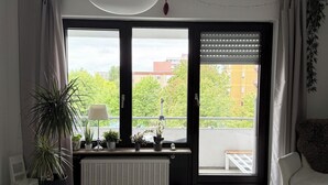 A modern living room with a sofa, a coffee table, a radiator, and a large window with blinds. - Seerhein apartment (Konstanz)