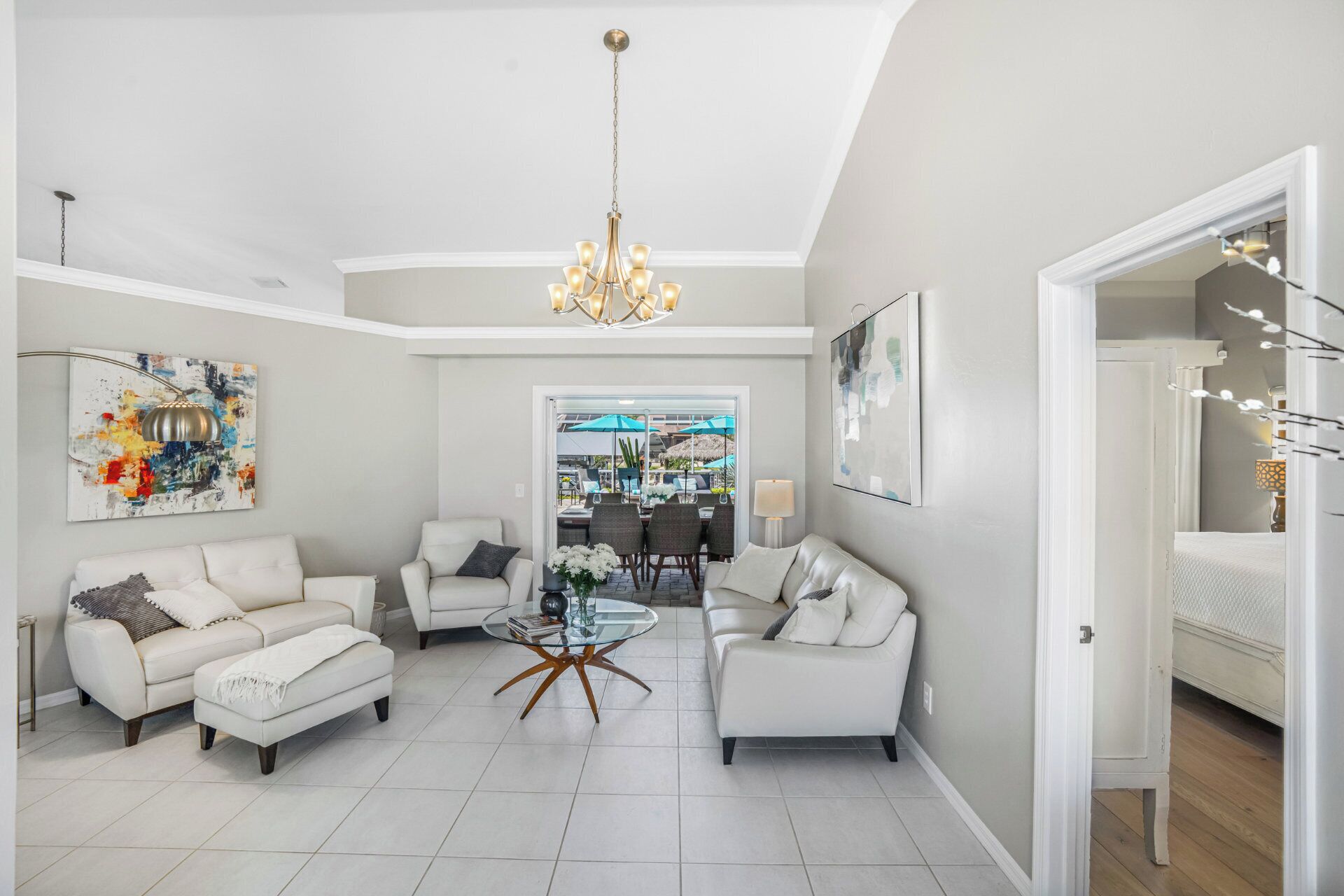 A spacious living room with a high ceiling, a chandelier, and a view into a dining area.
