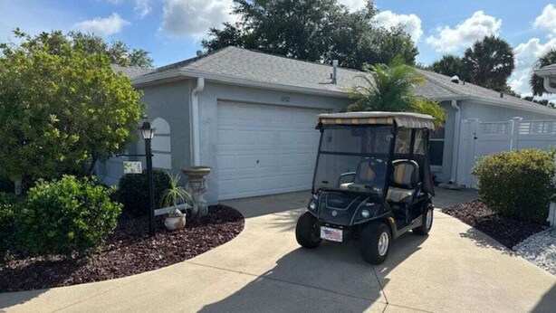 A golf cart parked in a driveway in front of a house with a garage. - 2 bdr/2 bth Courtyard Villa in The Villages w/ Cart Lake Sumter Spanish Springs (The Villages)