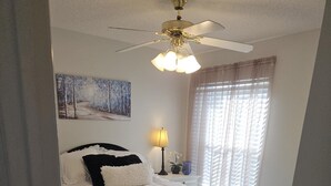 A bedroom with a bed, a ceiling fan, a window with blinds, and a painting on the wall. - 2 bdr/2 bth Courtyard Villa in The Villages w/ Cart Lake Sumter Spanish Springs (The Villages)