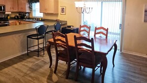 A spacious kitchen with wooden cabinets, a dining area with a large table and chairs, and a chandelier. - 2 bdr/2 bth Courtyard Villa in The Villages w/ Cart Lake Sumter Spanish Springs (The Villages)